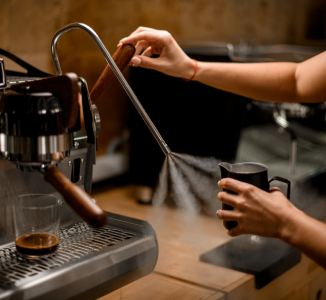 Coffee machine steam wand being cleaned